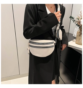 Detail of beige crescent crossbody bag featuring wide strap and detachable round pouch