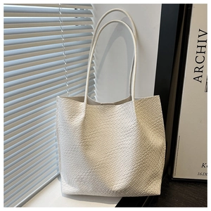 Detail of white woven tote bag showing the wide intrecciato texture and slim handles