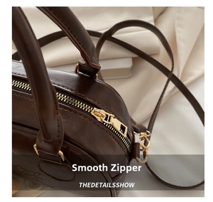 Close-up of smooth gold zipper and polished chocolate leather on retro shoulder bag