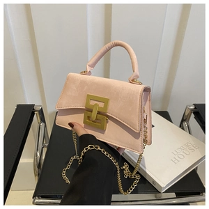 Close-up of pink suede crossbody bag with gold lock and chain strap detail