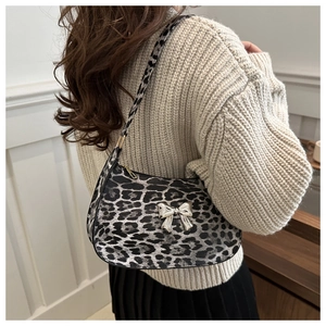 Detail of leopard print shoulder bag featuring a metallic silver bow and zipper closure