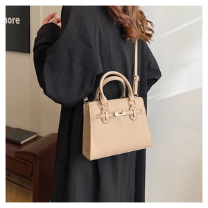 Detail of a beige faux leather handbag featuring a golden clasp and adjustable shoulder strap