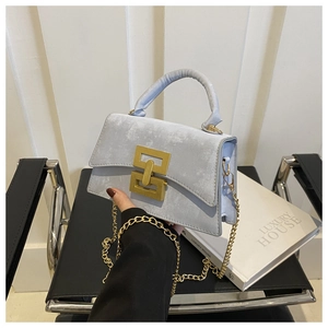 Close-up of light blue crossbody bag with gold rectangular lock and metal chain strap