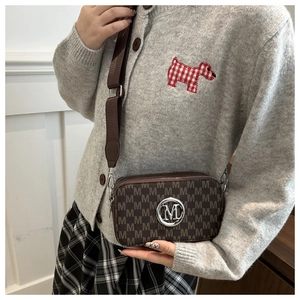 Close-up of brown letter print camera bag with dual zippers and wide textile strap