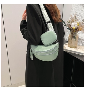 Detail of light green crescent bag with wide geometric strap and mini pouch on blazer