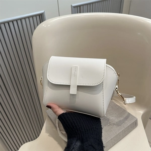 Minimalist white faux leather crossbody bag with golden hardware shown in a lifestyle setting