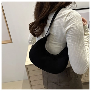 Close-up of black crescent underarm bag with matte texture and silver buckle on model