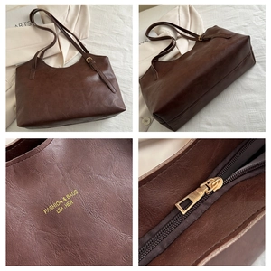 Macro detail of dark brown tote bag with gold logo lettering and metal zipper hardware