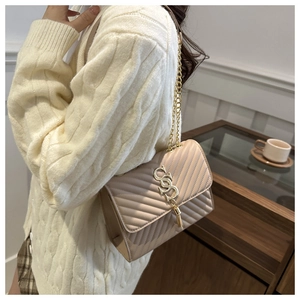 Detail of beige quilted flap bag featuring golden chain strap and metallic tassel
