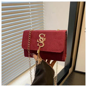 Detail of burgundy suede crossbody bag featuring gold double S metal clasp and tassel