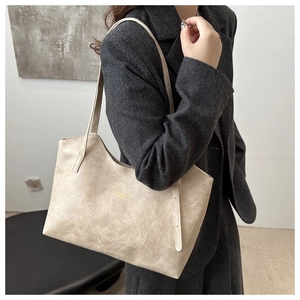 Detailed view of cream textured leather tote bag worn with a charcoal blazer