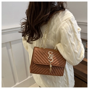 Detail of brown quilted bag with gold V-pattern, SS lock, and chain strap on white sweater