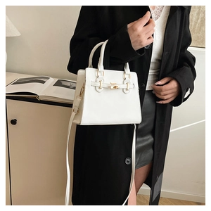 White leather handbag with gold lock shown in a stylish fashion lifestyle setting