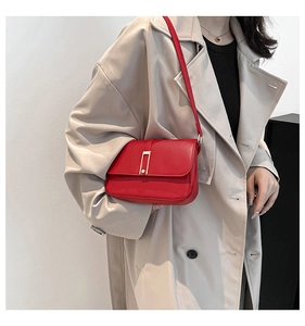 Detalle de bolso bandolera de cuero rojo con hebilla dorada mostrado en una modelo