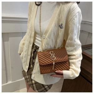 Detail of brown quilted leather bag featuring gold SS logo and elegant chain strap