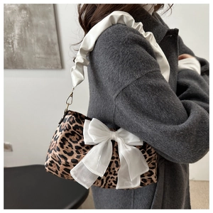 Close-up of leopard print shoulder bag with oversized white satin bow and ruched strap
