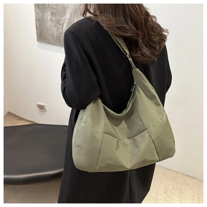 Vista dettagliata della borsa tote grande in nylon verde oliva indossata sulla spalla
