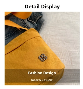 Close-up of bright yellow nylon shoulder bag featuring a grey four-ring metal logo