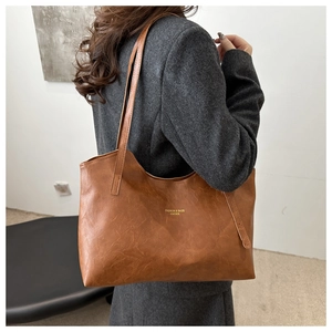 Close-up of brown leather tote bag detail with gold logo and premium textured surface