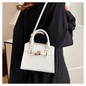 Lifestyle view of white leather crossbody bag with gold lock and black coat contrast