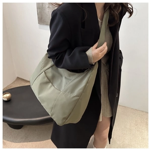Dettaglio della borsa tote in tela verde salvia con particolari plissettati trapuntati