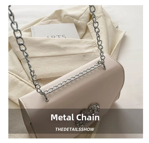 Detail of beige leather crossbody bag featuring silver chain strap and crystal buckle