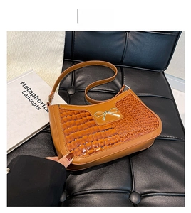 Détail de la texture motif crocodile et boucle dorée sur le sac marron