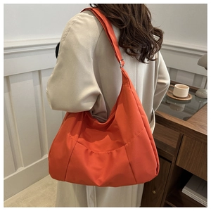 Dettaglio della borsa a mezzaluna arancione vivace in nylon con tracolla ampia regolabile