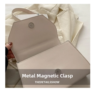 Detail of high-quality metallic magnetic closure on cream white leather shoulder bag