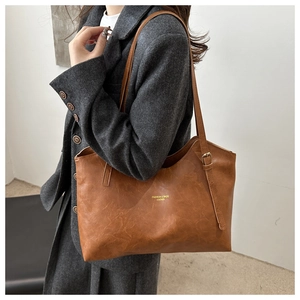 Close-up of brown vintage leather tote bag with gold lettering shown on shoulder