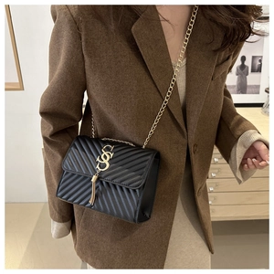 Detail of black quilted leather crossbody bag with gold chain strap and tassel