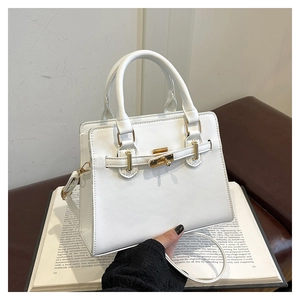 Detail of white Kelly-style handbag with gold twist lock on vintage books display