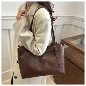 Detail of vintage brown leather tote bag with gold logo and adjustable shoulder strap