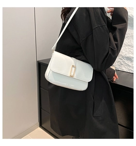 Detalle de bolso de hombro en cuero blanco brillante con hebilla dorada en un modelo