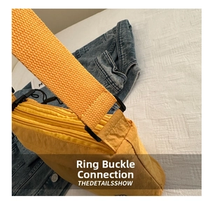 Detail of yellow nylon bag with wide woven strap and multi-layer zippers on denim background