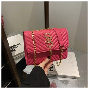Close-up of rose red quilted leather bag featuring gold V-stitch and tassel charm detail