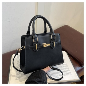 Detail view of black Kelly handbag with golden twist lock and adjustable shoulder strap