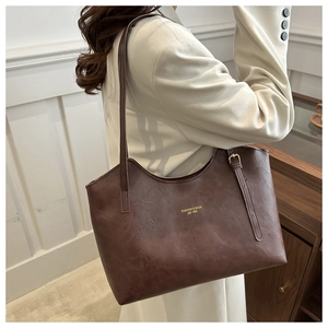 Detail view of large dark brown leather tote bag with gold lettering and adjustable strap