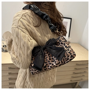 Dettaglio borsa leopardata con grande fiocco in velluto nero e tracolla arricciata