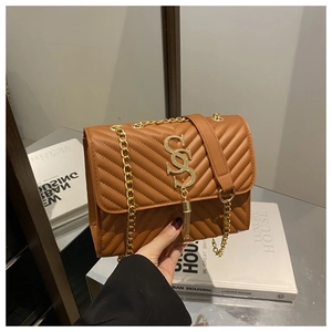 Detail of brown quilted bag with gold chain strap and elegant metallic tassel