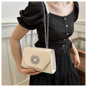 Detail of off-white crossbody bag with oversized rhinestone buckle and silver chain strap