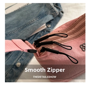Detail showing smooth zippers and metallic floral logo on a pink multi-layer crossbody bag