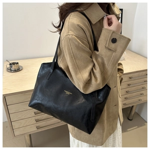 Detail of the minimalist black leather tote bag featuring gold FASHION & BAGS lettering