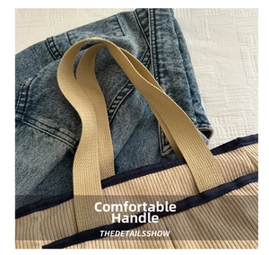 Detail of beige corduroy tote bag featuring brown woven handles and navy trim accents