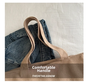 Close-up of beige corduroy tote bag handles showing detailed ribbed texture and stitching