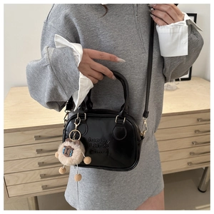 Detail of black leather bag featuring lucky LHCO engraving and alpaca plush charm accessory