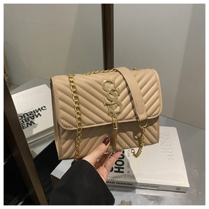 Detail of beige V-quilted crossbody bag with gold S-logo and chain tassel accent