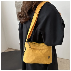 Detail of yellow nylon crossbody bag featuring stylish crinkled texture and silver logo