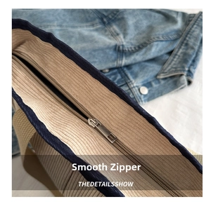 Detail of smooth metal zipper closure on a durable canvas tote bag with navy blue trim