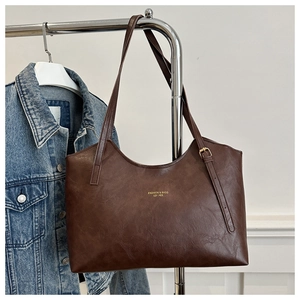 Detail of dark brown tote bag with gold lettering and slim shoulder strap